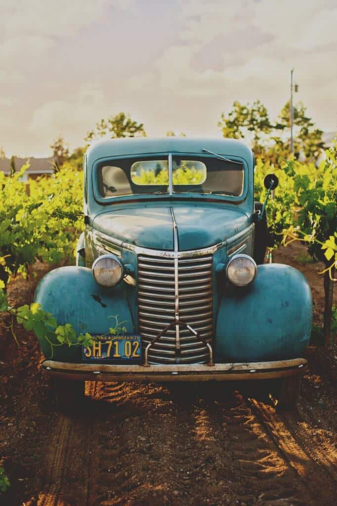 Old truck in farm field. Buy an old car to boost your travel savings account.