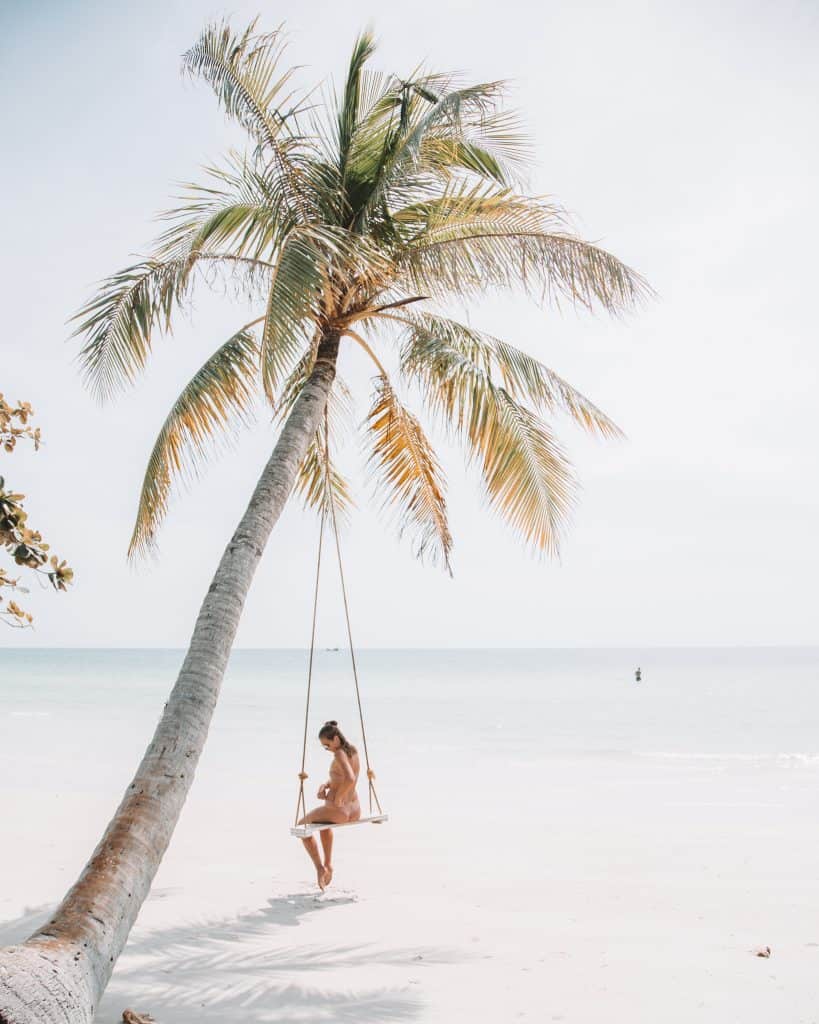 woman swinging under palm tree in florida